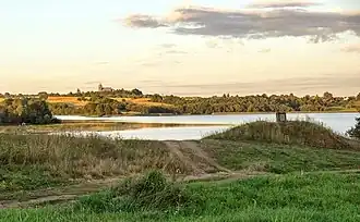 Вид на озеро Мнюта и костёл[бел.] со стороны деревни Озёрки[бел.] в 2015 году