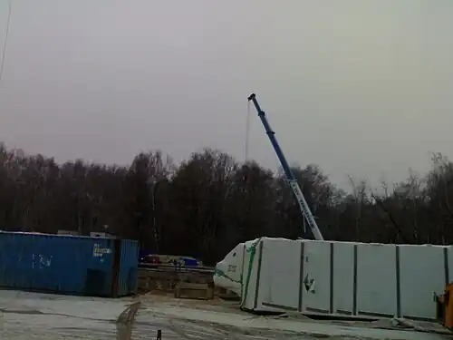 Между хозяйственными постройками виден котлован