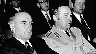 Слева: доктор Манфред Мессершмидт, старший историк Управления военной истории MGFA 1970–1988, на лекции по политике безопасности в Управлении исследований военной истории MGFA. Справа: бригадный генерал Вольфганг Альтенбург, впоследствии генеральный инспектор вооруженных сил Германии.