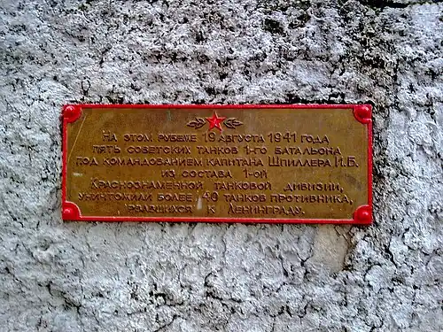Памятная доска сбоку постамента памятника сообщает: «На этом рубеже 19 августа 1941 года пять советских танков 1-го батальона под командованием капитана Шпиллера И. Б. из состава 1-й Краснознамённой танковой дивизии, уничтожили более 40 танков противника, рвавшихся к Ленинграду».