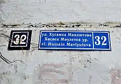 Современный трёхъязычный вариант адресной таблички: ул. Мавлютова, 32 – используется ненормативное написание фамилии на татарском языке, а также содержится ошибка в местоположении сокращённого слова St (ноябрь 2018)