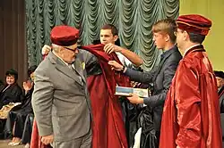 Студенты помогают Альфреду Овоцу надеть мантию