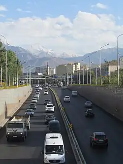 Вид с перекрестка улиц Саина-Шаляпина  в направлении на юг; на заднем плане пик Советов и Большое Алматинское ущелье (сентябрь 2014-го года)