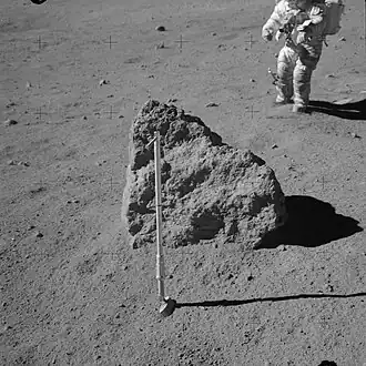 Третий валун, который Янг и Дьюк не смогли перевернуть на Station 8. На заднем плане Джон Янг. Молоток в его подколенном кармане. На переднем плане&nbsp;— совок в роли гномона