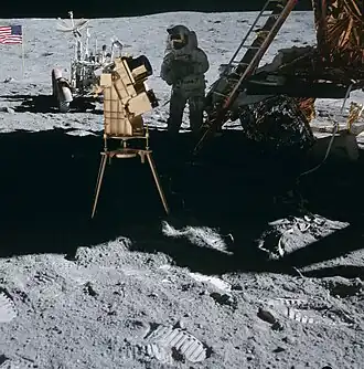 Ультрафиолетовый, позолоченный телескоп UVC в тени посадочного модуля. За ним&nbsp;— Чарли Дьюк