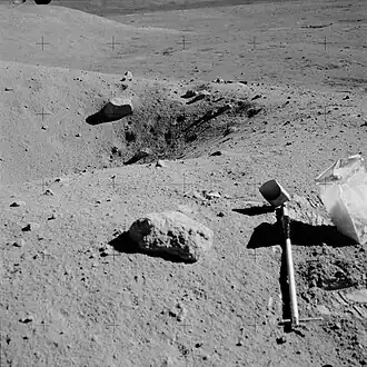 Ballet Crater. За ним слева склон эскарпа. На переднем плане справа&nbsp;— совок и контейнер для образцов