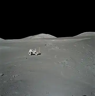 Шмитт у «Ровера» на Station 4. Между «Ровером» и валуном видно пятно оранжевого грунта. Справа&nbsp;— кратер Шорти