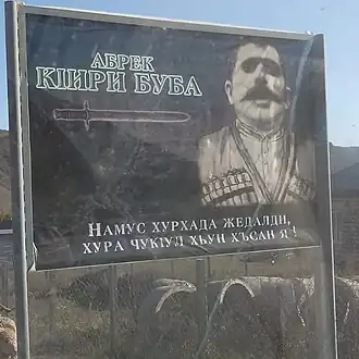 Плакат с абреком в селе Кири с цитатой: «Лучше нож в груди, чем честь в грязи
