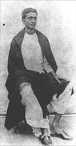 A photo of a sitting young Indian man wearing spectacles and looking to the right
