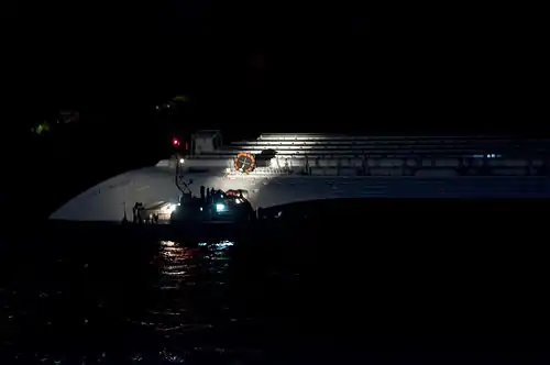 Катер у левого борта, на котором лежат застрявшие спасательные плоты