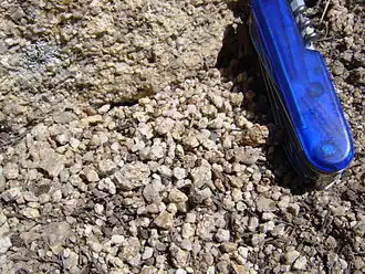 Гранитоид (вверху) рассыпается в дресву. Ширина ножа&nbsp;— около 2 см.