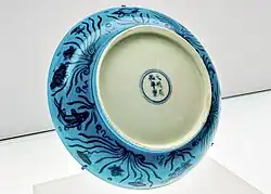 Цзиндэчжэньская тарелка с сине-белым рисунком под бирюзовой глазурью с лотосов и рыб, период правления императора Сянь-цзун (1465–1487). Восточный филиал Шанхайского музея.