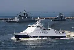 ПСКР «Надёжный» проекта 22460 из состава ПУ ФСБ России по Калининградской области на военно-морском параде Балтийского флота в честь празднования Дня ВМФ в Балтийске (2018 год).На заднем плане слева направо: корвет «Стерегущий» и малый ракетный корабль «Зыбь» ВМФ России.