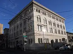 A color photo of a beige four-storied building with arched windows and ornate roof