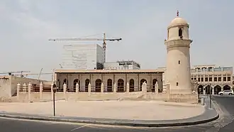 Минарет старой мечети стоит перед строящимся Национальным архивным зданием в квартале Диван-Амири в центре Дохи Мушейреб