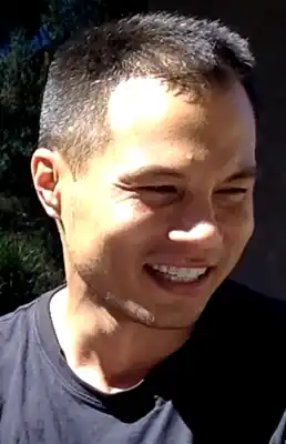 35-year-old man smiling to the right of the camera.