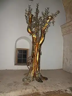 Символическое оливковое дерево с колосьями у корня, обвитое виноградной лозой. Вероятно отсылка к словам ап. Павла (Рим.&nbsp;11:17-24)